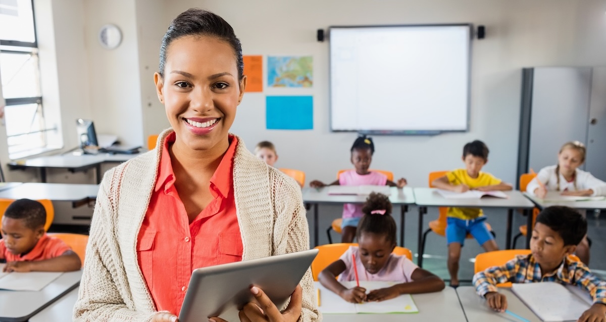 Miced race teacher posing in front of class with tablet pc 740520